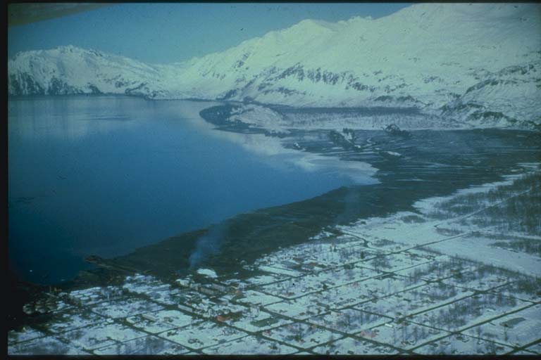 Aufnahme der Hafengegend von Valdez, Alaska, kurz nach dem Tsunami von 1964. Angesichts der dunklen Landflächen ist das Ausmaß der landeinwärts gerichteten Verwüstungen deutlich sichtbar.