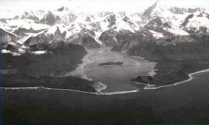 Die Lituya-Bay in Alaska, 1958: deutlich erkennbar sind die hellen Ufergebiete in der Bucht, die von dem 520 Meter hohen Mega-Tsunami überflutet und dabei völlig verwüstet wurden. Ursache war ein Teil der Felswand in der Bucht, der in einer Höhe von 1100 Metern abgebrochen und ins Wasser gerutscht war. © Universidad de Puerto Rico